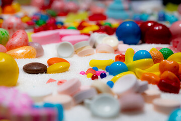 Confectionery and glaze coated candies on the table. Shallow depth of field. Variety of holiday sweets, marshmallows, colourful sugar dessert, caramels, stripes, swirls, on the table. Macro.