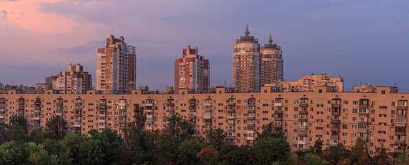 Sunset cityscape with architecture City urban landscape. Tall long building, high-rise buildings on light backdrop design. Purple Evening panoramic town. Many windows in horizontal skyline