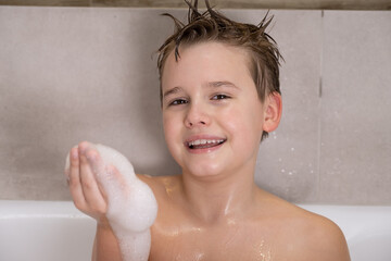 Funny boy playing with water and foam in a bathroom Cute happy child bathe at home healthy childhood