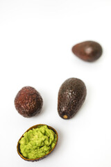 Fresh guacamole with ripe and delicious natural avocado on white background, traditional mexican dip sauce in a half avocado black rind.  Close-up photo. Concept of healthy traditional mexican food