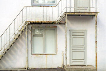 White wooden door and window in an old frame. Stairs to the second floor.
