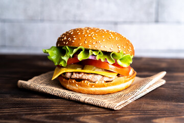 hamburger with cutlet, tomato and cheese on a dark wooden table and paper