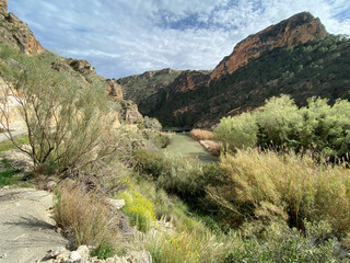 view of a hiking trail along the river with rocks, mountains and lots of vegetation in Spain