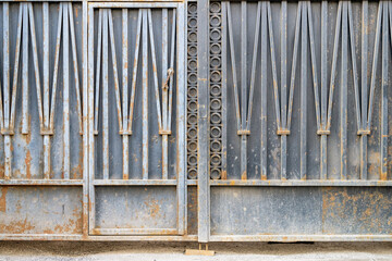 Black metal gate with traces of rust and an entrance door