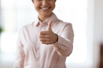Crop close up blurred view of smiling ethnic woman show thumb up give recommendation to online course or training. Happy mixed race female recommend good service or company. Success concept.