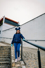 happy little girl on the stairs in blue winter clothes