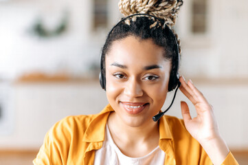Close up portrait of a confident satisfied young african american woman wearing headphones, call...