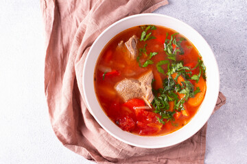 Shurpa soup in a white plate on a pink cloth. Turkish cuisine. 