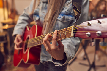 Obraz premium Close-up of woman learning to play electric guitar during musical lesson in studio