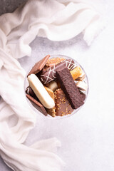 Cookies with chocolate and rehams in a round crystal vase on a white cloth. View from above. 