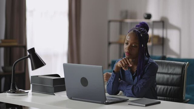 afro-american woman is looking on screen of laptop and listening learning webinar or online lecture
