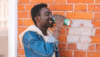 Portrait of happy young african man drinking coffee on a city street