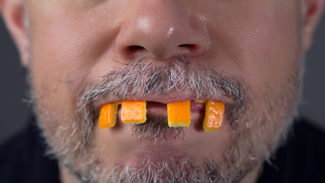 Man Playing With Orange Peel. Fake Teeth