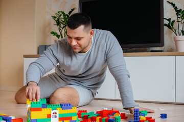 Fototapeta premium A little boy together with his father is played by a constructor and builds a house. Construction of a family home.