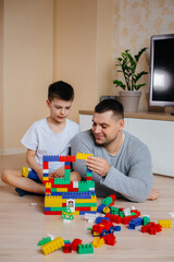 A little boy together with his father is played by a constructor and builds a house. Construction of a family home.