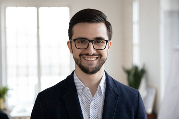 Profile picture of smiling young Caucasian businessman in suit and glasses pose in modern office....