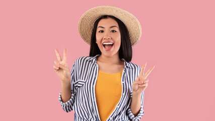 Portrait of smiling asian woman showing peace victory sign gesture