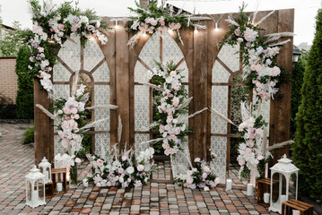 Fototapeta na wymiar a large wooden wedding photo zone decorated with flowers. wooden wedding arch with windows. wedding decor. holiday photo zone for guests
