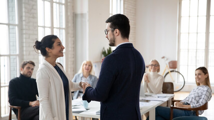 Businessman shake hand of excited Indian female employee welcome in new company workplace. Male...