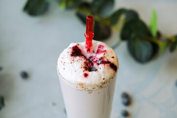 Glass of milkshake with blueberries sprinkled with chocolate chips.