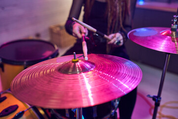 Obraz premium Close-up of female drummer using sticks while playing on drums during performing