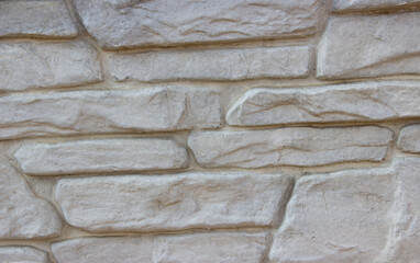 Texture of a stone wall from long and stones of different sizes. Gray long stone wall