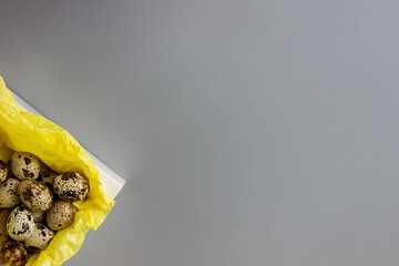 Quail eggs in a white box on yellow paper, minimalism. elegant easter background, space for text, copy space,