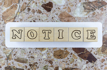 Notice - design template with alphabet letters on wooden cubes arranged over a white sign centered on a marbled stone background with copyspace