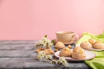 Obraz na płótnie Canvas Almond cookies and a cup of coffee on a gray and pink background. Side view, selective focus, copy space.