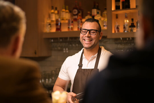 smiling and sociable bartender conducts a conversation with customers in the bar