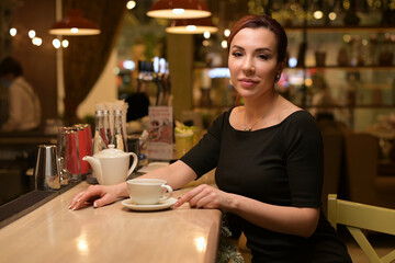 Portrait of a young beautiful woman at the bar who drinks tea
