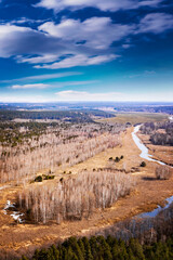 Forest landscape with sky, field and river. Spring sunny day, wild European nature. Beautiful sky. Top view, aerial photography. 