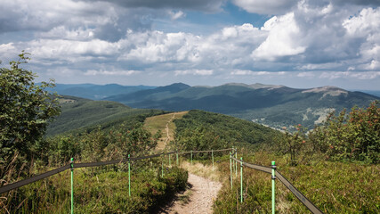 An empty trail leading through the mountain peaks on a sunny, warm day, Bieszczady Mountains, Poland