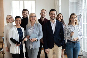 Group portrait of smiling diverse multiracial businesspeople stand pose in modern office show unity...