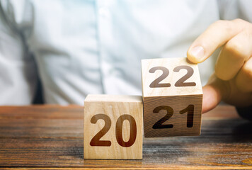 Hand flips a block changing 2021 to 2022. New year beginning. Holidays and Christmas. Trends and...