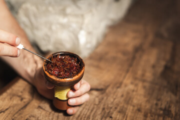 Process of making hookah for smoking. concept of smoking a hookah and having a good time. laying tobacco in a hookah bowl close