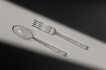 transparent spoon and fork cutlery in the sun with hard shadows. plastic pollution. pollution threat