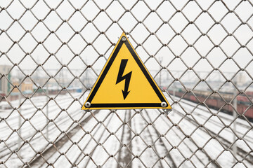 High voltage hazard warning sign on the background of the railway. 