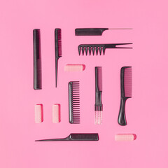 Collection of professional hairdresser combs and curlers arranged on pink background. Minimal flat lay concept.