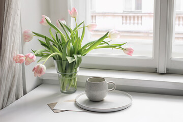 Easter spring still life. cup of coffee and floral bouquet on window sill. Pink tulips flowers in ceramic vase pot. Blank greeting card mockup. Home decor, breakfast concept. Scandinavian interior