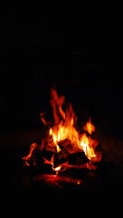 Mesmerizing fire with orange and red flames. In dark night time some wood chips are on fire.
