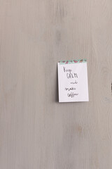 Reminder sticky note pasted with a butterflies adhesive on a wooden background with the sentence:...