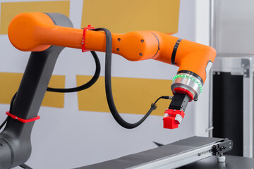 Orange pick and place robotic clamp arm manipulator moving red toy blocks at modern robot trade...