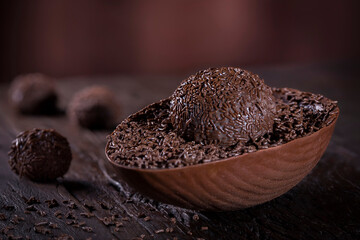 Chocolate Easter egg stuffed with brigadeiro on rustic wooden background. Image with selective focus.