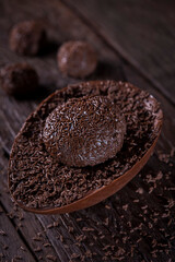 Chocolate Easter egg stuffed with brigadeiro on rustic wooden background. Image with selective focus.