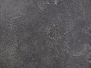 The texture of a dark gray concrete floor slab with dirt and sand. Simple industrial, factory background.