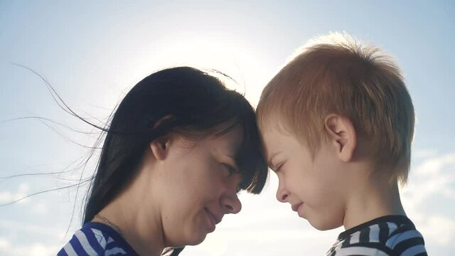 son and mom cute video concert mother's day. teamwork happy family boy kisses mother on lifestyle the cheek touches his nose. parent takes care of the child. kid and adult woman mom in the sunlight at