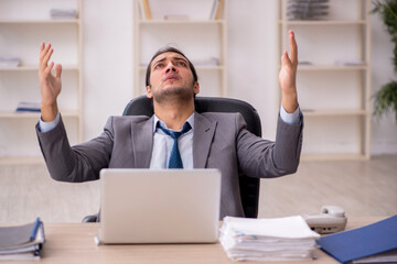 Young male employee unhappy with excessive work in the office