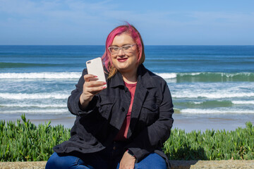 Beautiful fat woman using cell phone to watch social media videos on the beach. chubby model, selfie