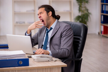 Obraz premium Young male employee unhappy with excessive work in the office
